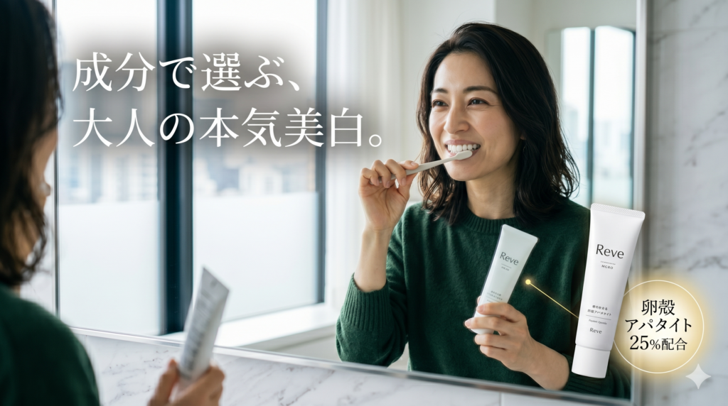 明るい洗面所の鏡の前で、深緑のニットを着た40代の日本人女性が、白いオーガニック歯磨き粉「Reve」のチューブを手に持ちながら、丁寧に歯ブラシでブラッシングをしている。鏡には『成分で選ぶ、大人の本気美白。』という白いテキストが浮かんでいる。