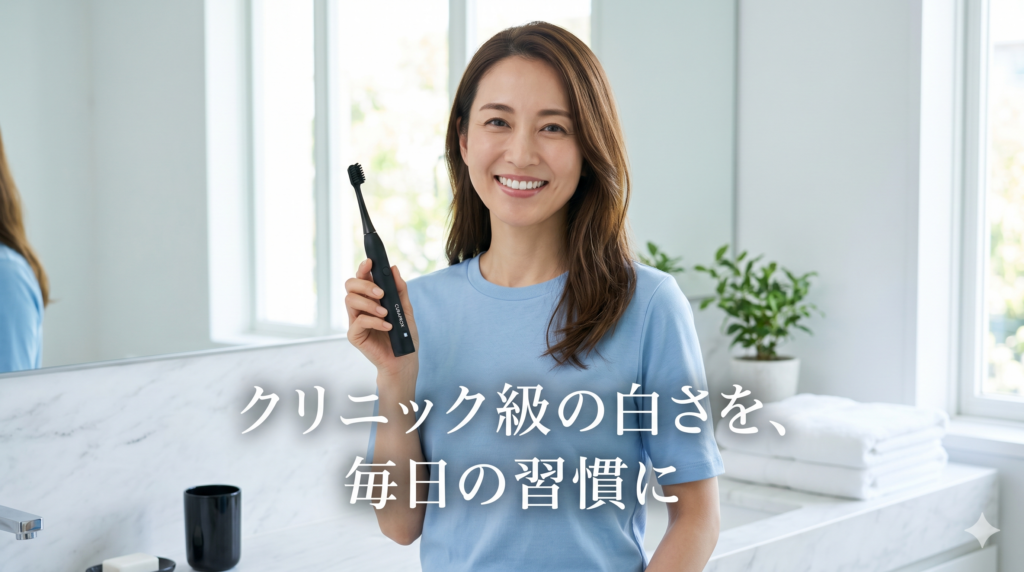 ミディアムロングヘアーの40代女性が、爽やかなブルーのTシャツを着て、自宅の洗面所でクラプロックス ブラックisホワイト電動歯ブラシを片手に笑顔で立っている画像
